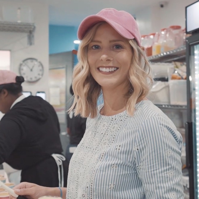 Woman looking and smiling directly at the camera while wearing a pink hat