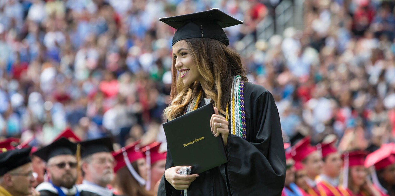 A female student holds her diploma at commencement